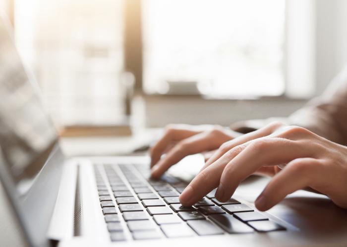 Fingers typing on laptop keyboard.