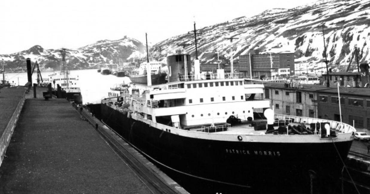 Ship docked with hills covered in snow in the background
